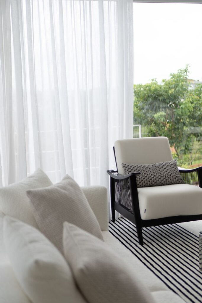 Mastering the First Impression: Your intriguing post title goes here Minimalist white armchair by window with sheer curtains and greenery outside.
