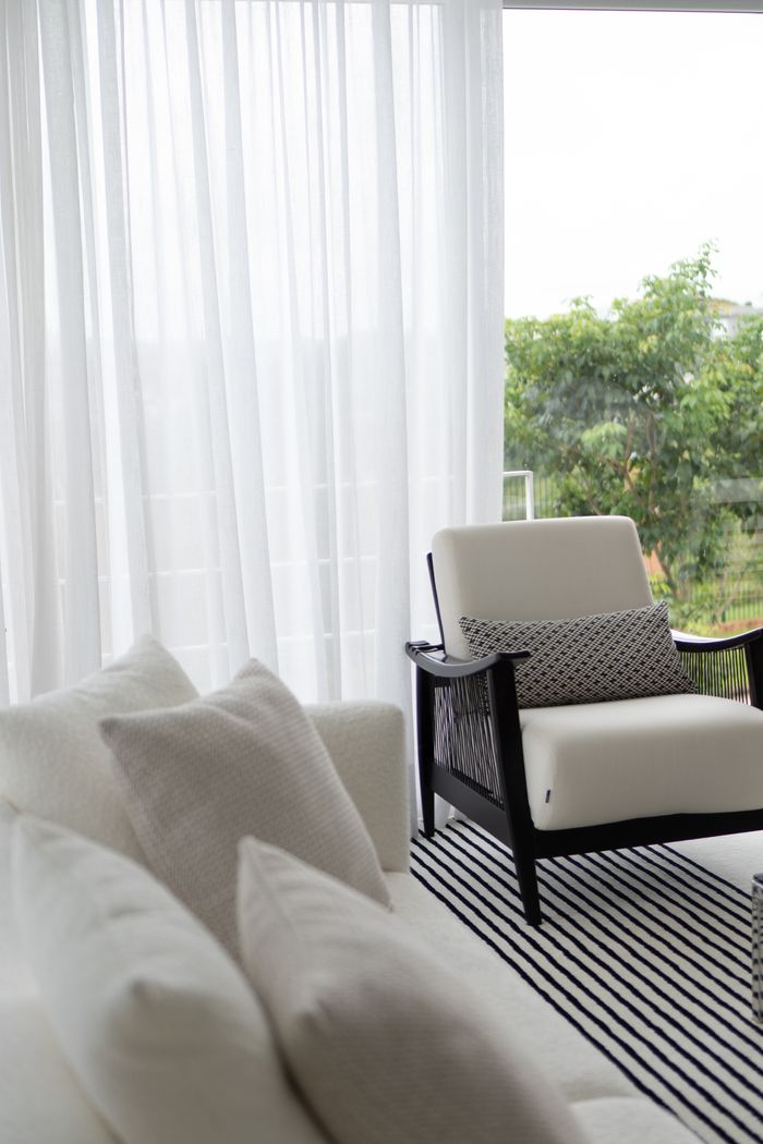 Mastering the First Impression: Your intriguing post title goes here Minimalist white armchair by window with sheer curtains and greenery outside.