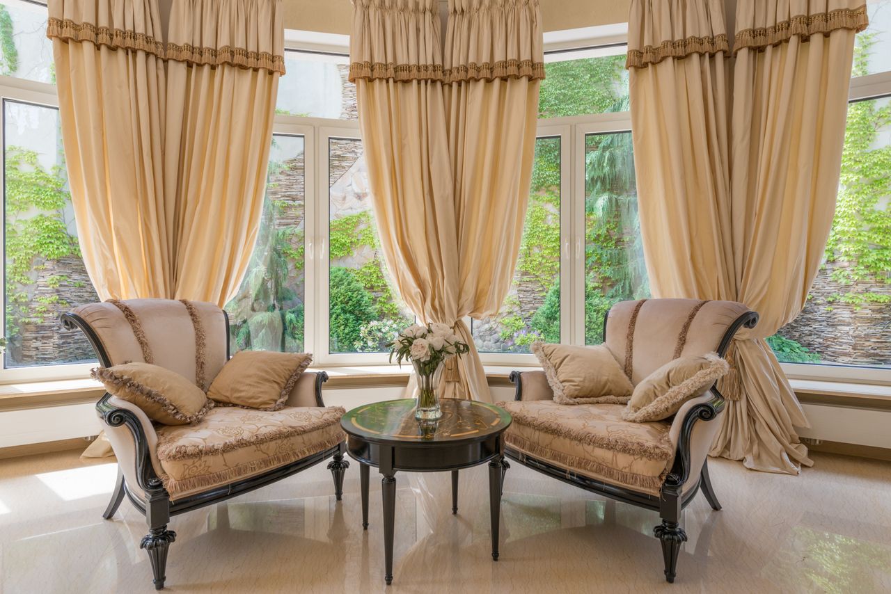 The Art of Drawing Readers In: Your attractive post title goes here Interior of luxurious living room with table decorated with vase with flowers near armchairs and windows with beige curtains
